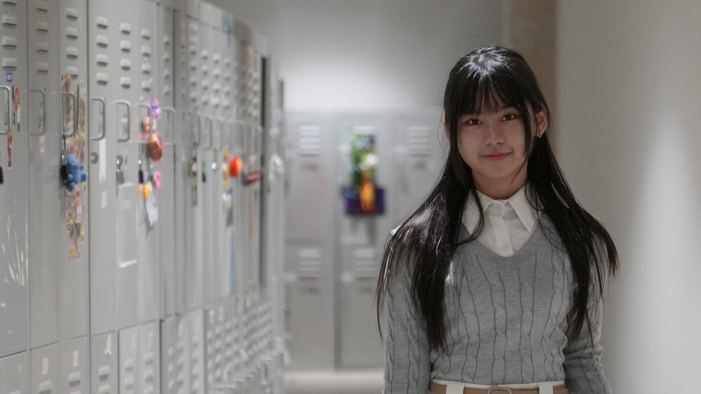 Kellyn Wu standing in a school corridor lined with lockers
